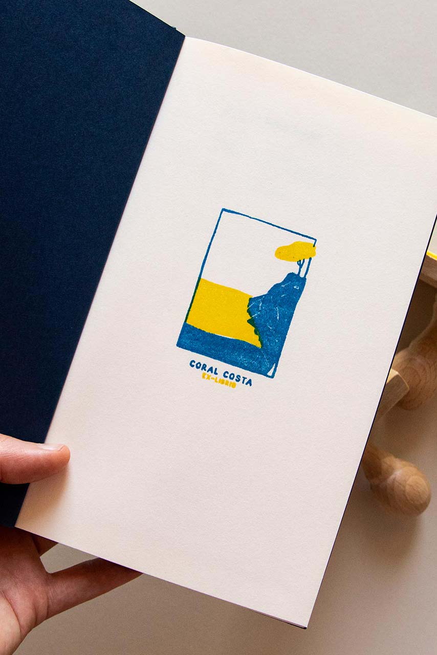 Portadilla de libro estampada con sello exlibris de una playa con un acantilado