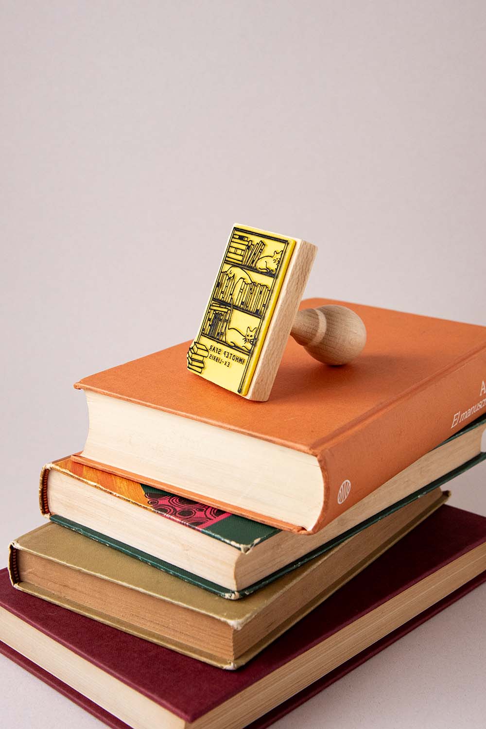 Sello ex-libris con una estantaría llena de libros y tres gatos