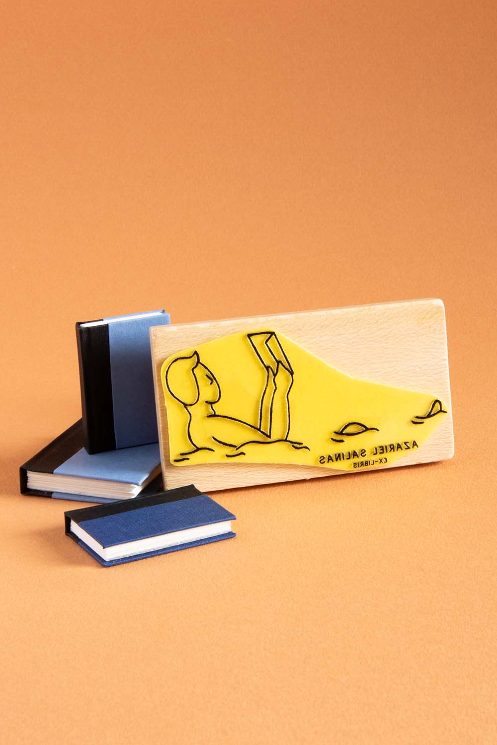 Sello exlibris grabado de una persona leyendo un libro mientras nada