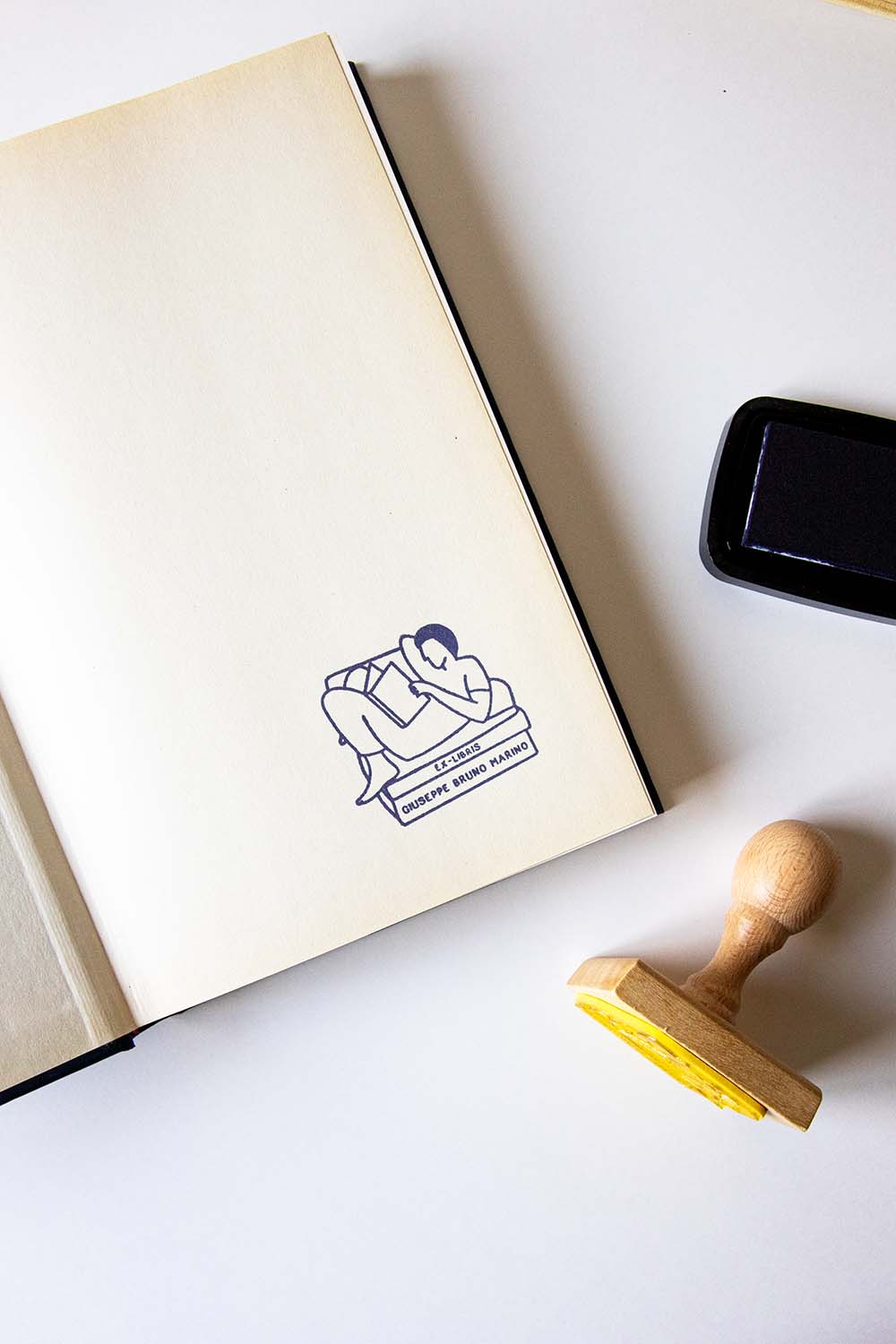 Portadilla de libro estampada con un hombre leyendo en un sillón y sello