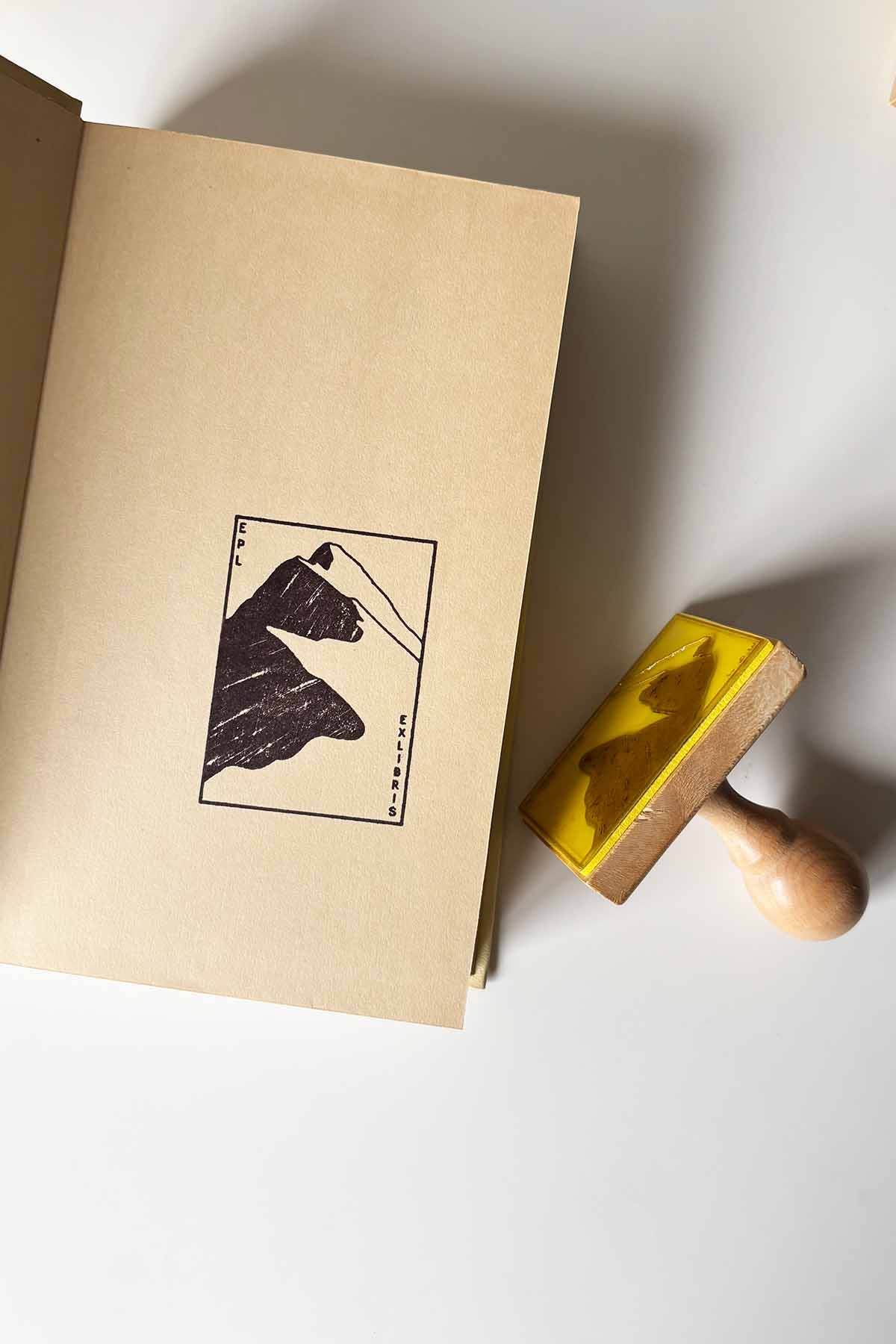 Portadilla de libro estampada con una montaña y sello
