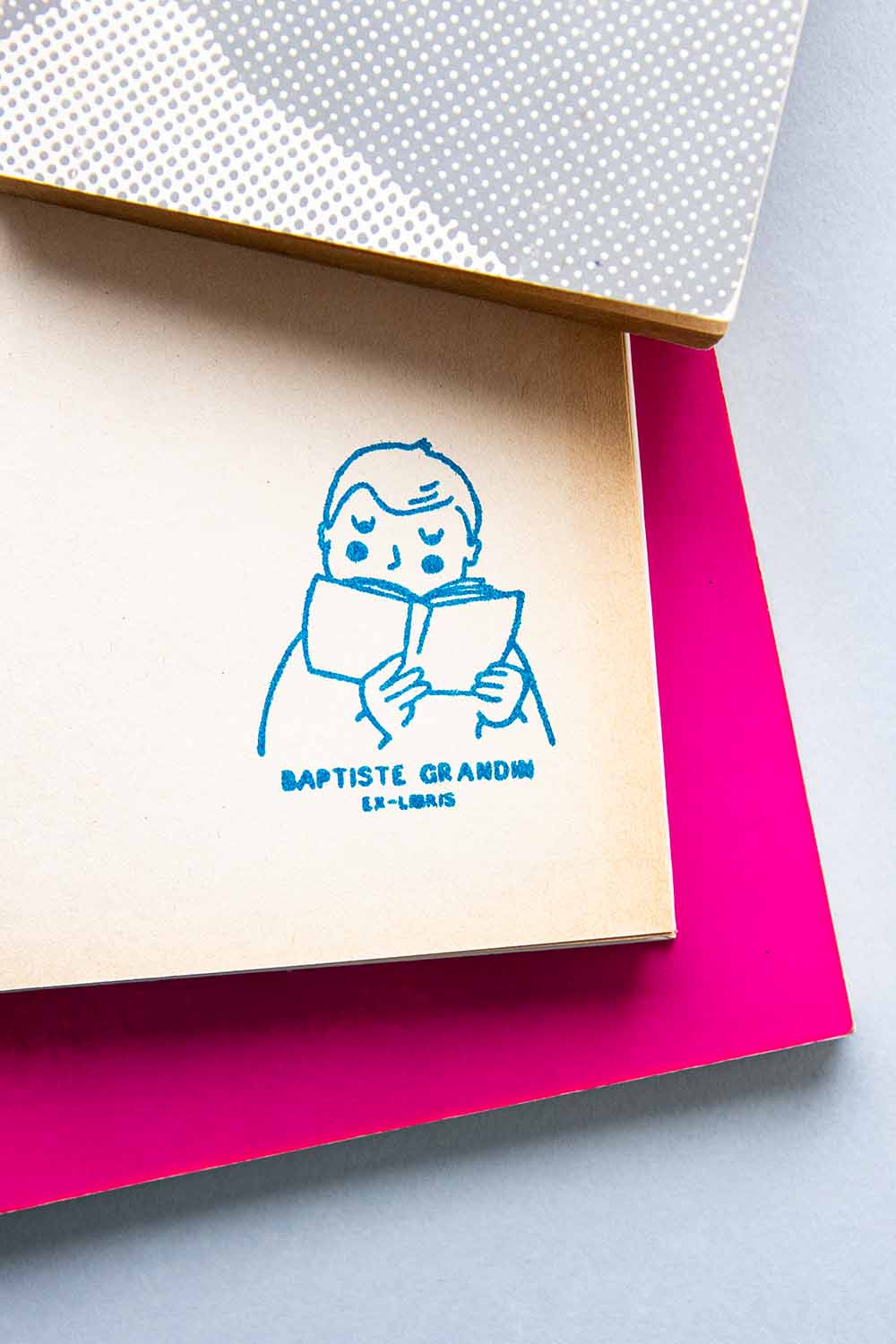 Portadilla de libro estampada con sello exlibris de un niño leyendo