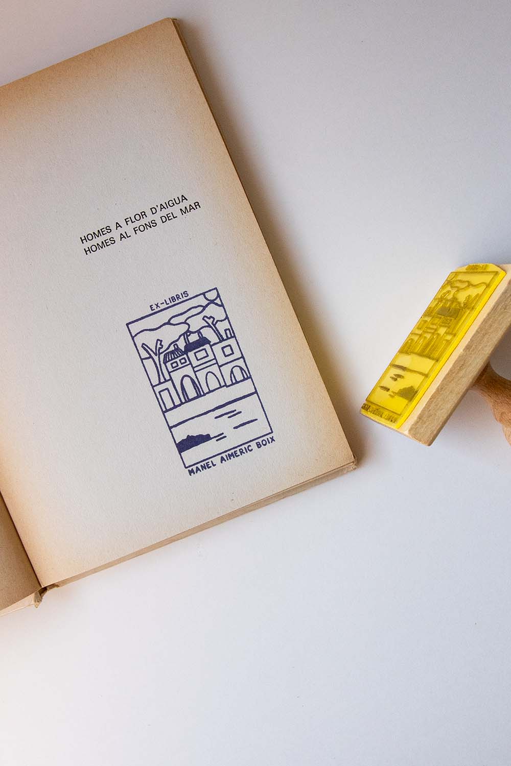 Portadilla de un libro estampada con un pueblo de costa y sello