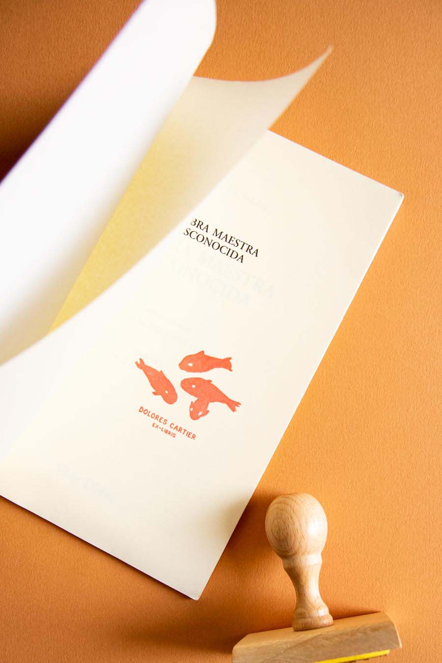 Portadilla de libro estampada con peces rojos nadando en diferentes direcciones y sello
