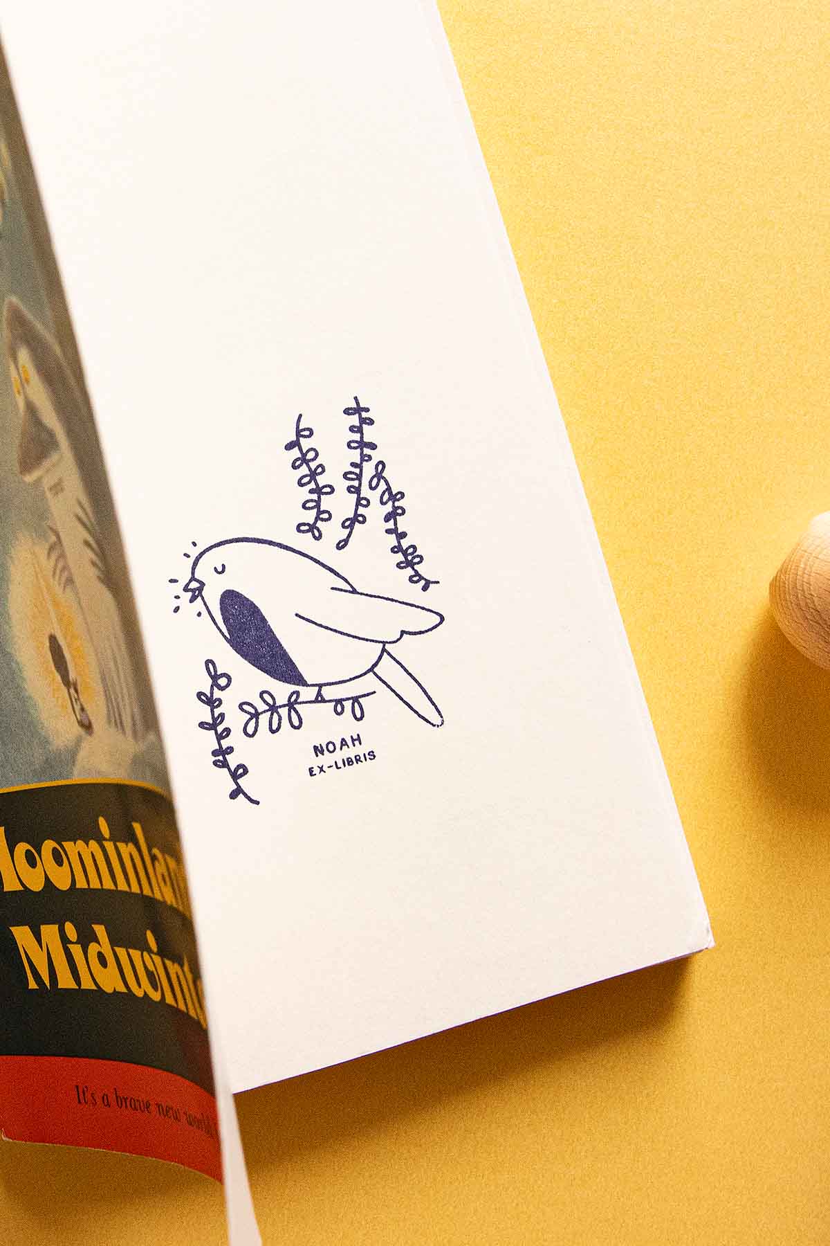 Portadilla de libro estampada con sello exlibris de un pájaro petirrojo cantando y sello