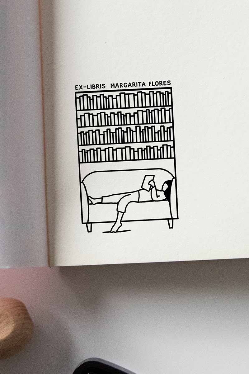 Portadilla de libro estampada con una chica estirada leyendo en un sofa y una biblioteca detrás