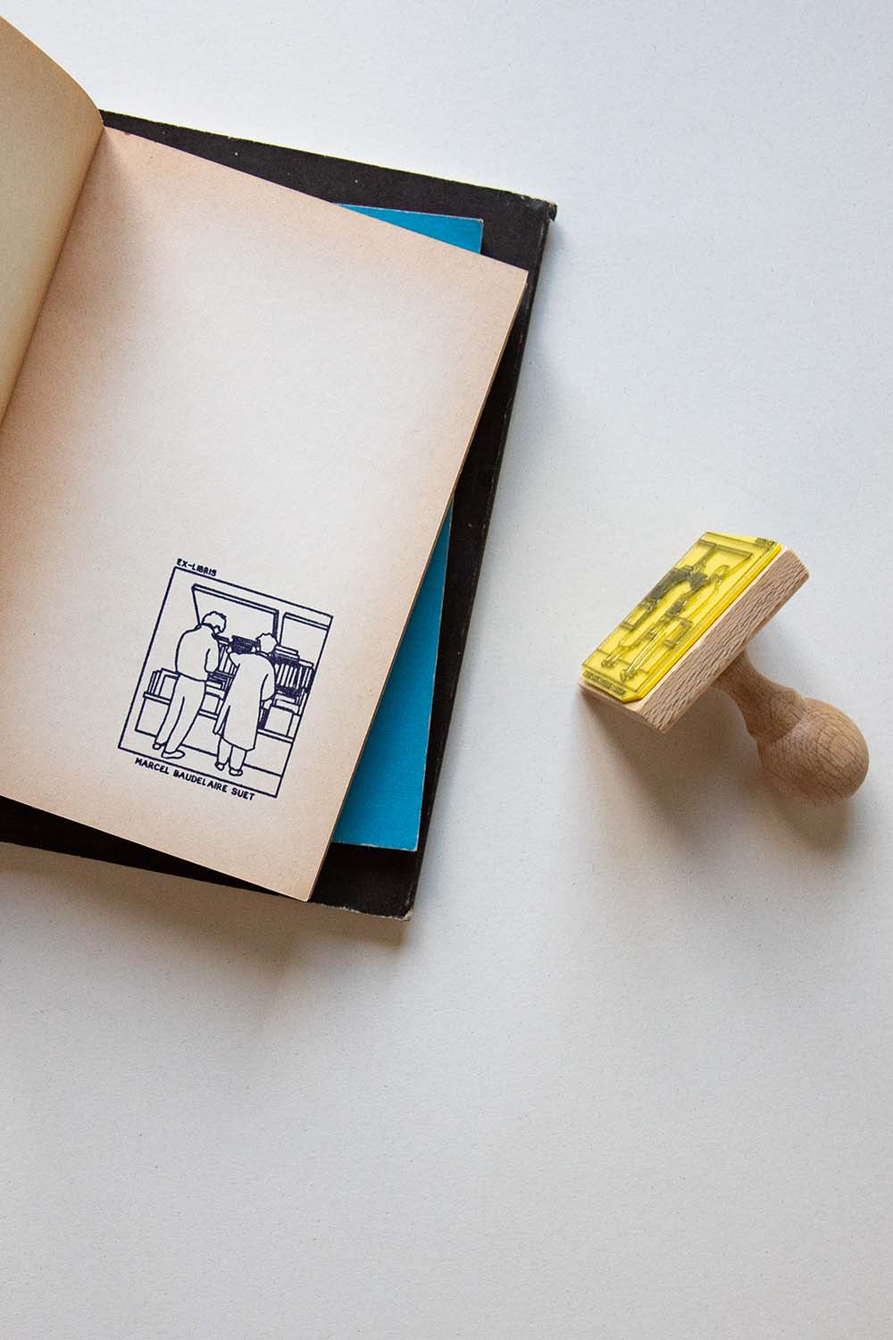 Portadilla de libro estampado con dos personas mirando los libros en los bouquinistes de París y sello