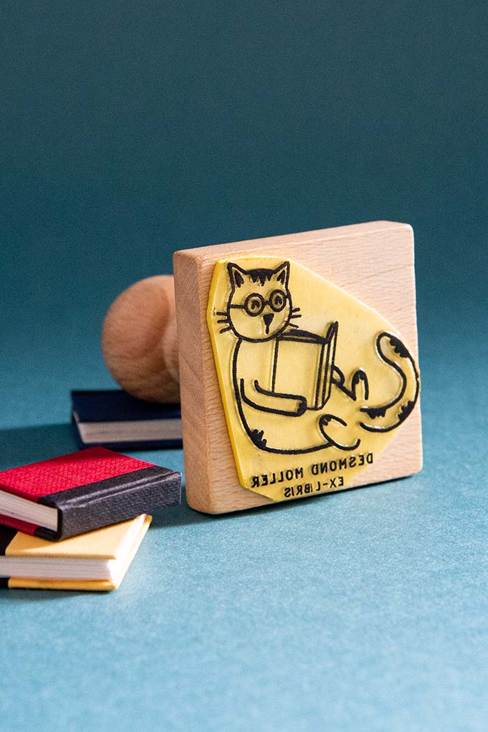 Sello ex-libris de un gato con gafas tumbado leyendo un libro