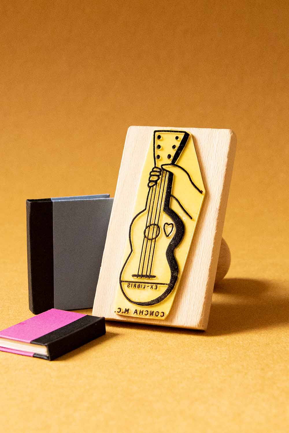 Sello ex-libris de una mano sosteniendo una guitarra