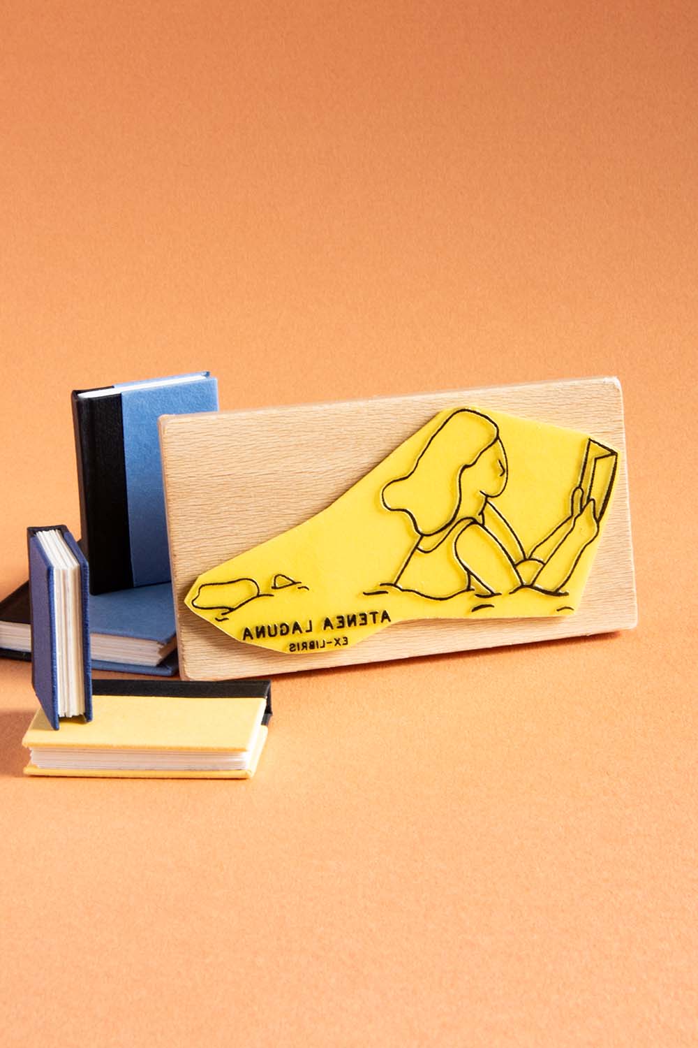 Sello exlibris grabado de una mujer nadando y leyendo un libro al mismo tiempo