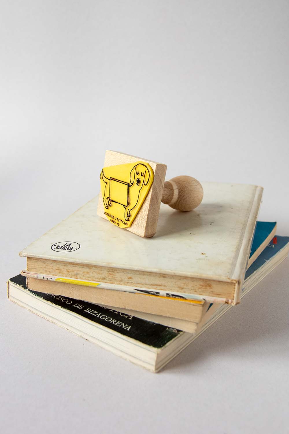 Sello exlibris grabado de un perro con un libro abierto sobre el lomo