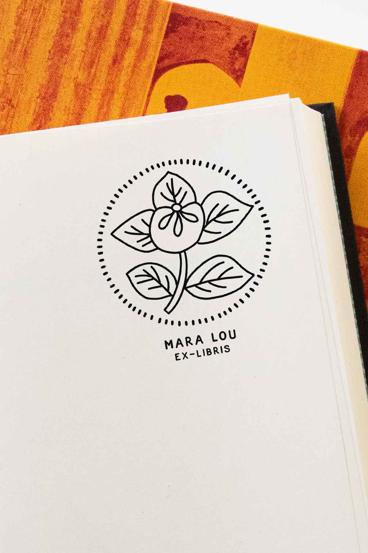 Portadilla de libro estampada con sello exlibris de una flor enmarcada en un círculo