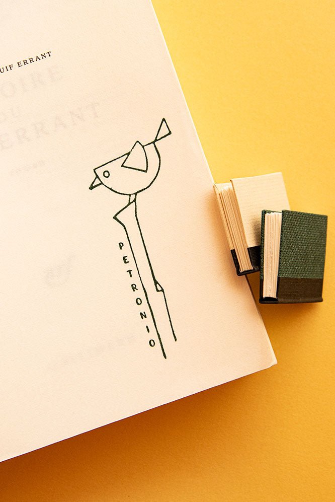 Portadilla de libro estampada con sello exlibris de un pájaro encima de un palo
